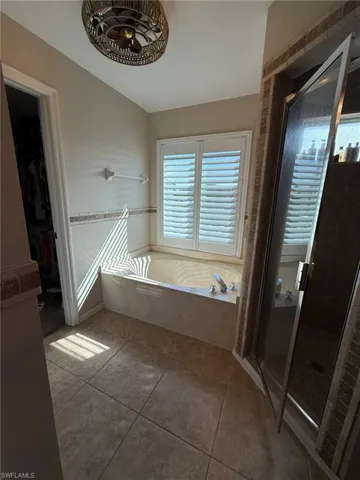 Bathroom featuring a spacious closet, a garden tub, a shower stall, and tile patterned floors