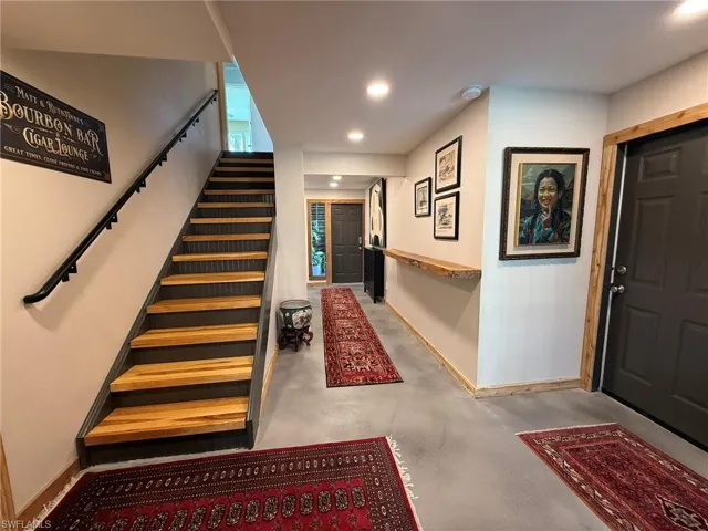 Foyer with concrete floors, stairs, baseboards, and recessed lighting