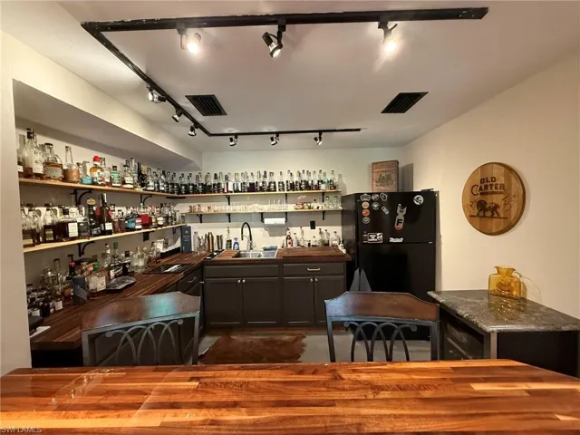 Bar featuring freestanding refrigerator, rail lighting, a sink, and wet bar