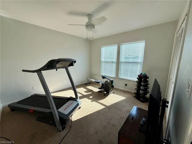 Workout area featuring ceiling fan, carpet floors, and baseboards