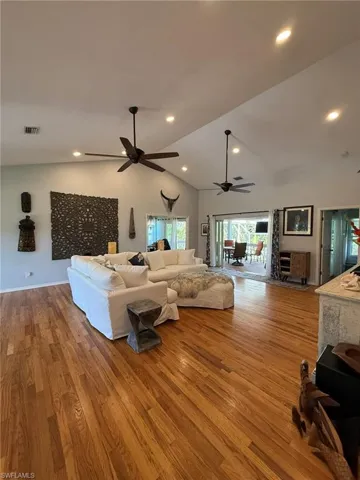 Living area with wood finished floors, visible vents, ceiling fan, lofted ceiling, and recessed lighting