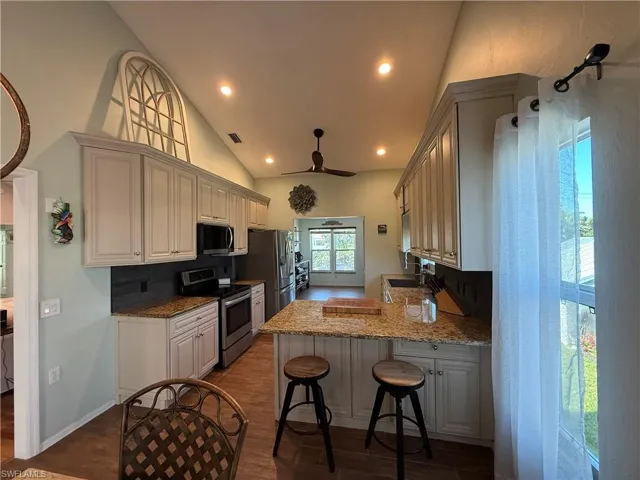 Kitchen with a peninsula, a ceiling fan, a sink, stainless steel appliances, and backsplash