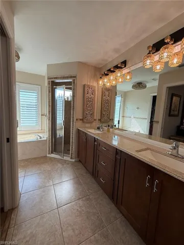 Bathroom with a stall shower, a sink, tile patterned flooring, a garden tub, and double vanity