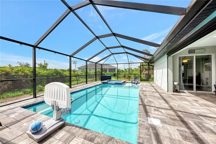 View of pool featuring an in ground hot tub, glass enclosure, and a patio area