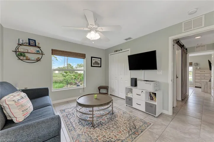 Living room featuring light tile patterned floors, a barn door, and ceiling fan