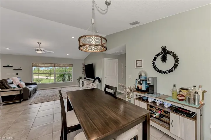 Tiled dining room with ceiling fan and vaulted ceiling