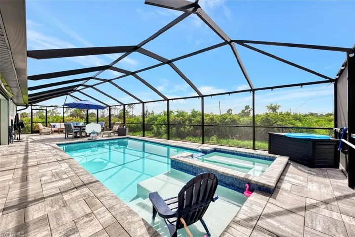 View of swimming pool with a patio, an in ground hot tub, and a lanai