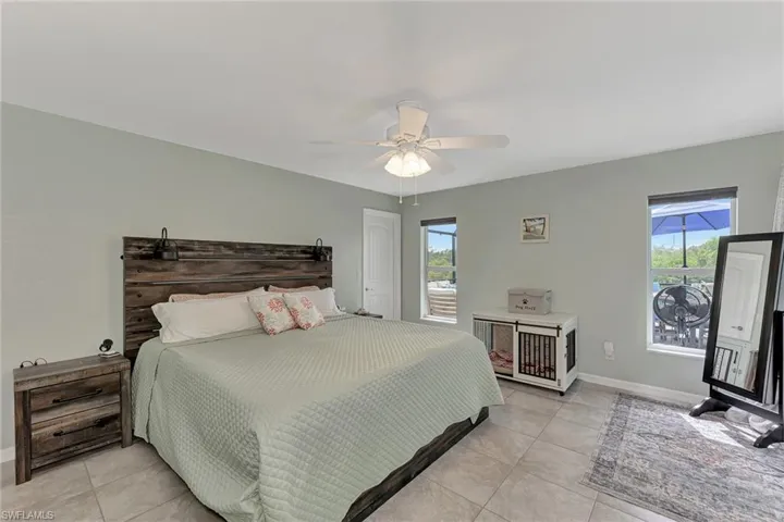 Bedroom featuring multiple windows, light tile patterned floors, and ceiling fan