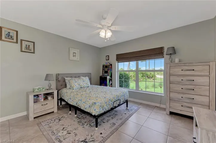 Tiled bedroom featuring ceiling fan