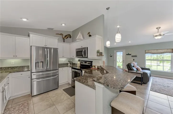 Kitchen featuring ceiling fan, stainless steel appliances, light tile patterned floors, and kitchen peninsula