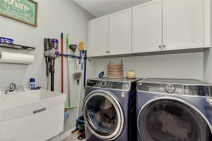 Clothes washing area with sink, cabinets, and independent washer and dryer