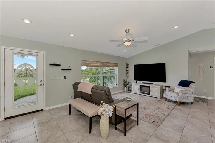 Living room with light tile patterned flooring, a wealth of natural light, ceiling fan, and vaulted ceiling