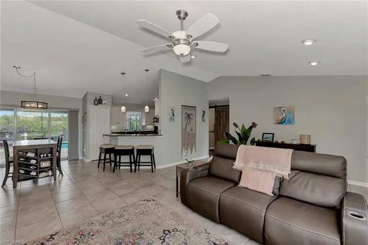Tiled living room with a barn door, lofted ceiling, and ceiling fan