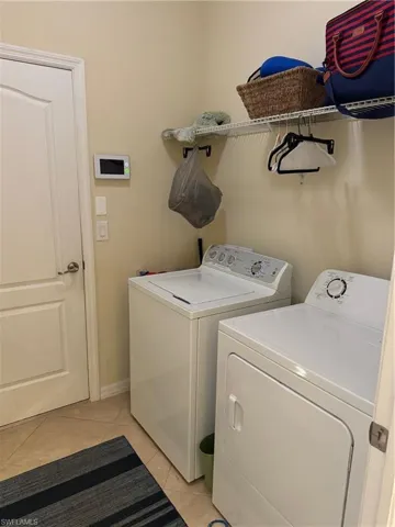 Laundry area featuring light tile floors and washing machine and clothes dryer