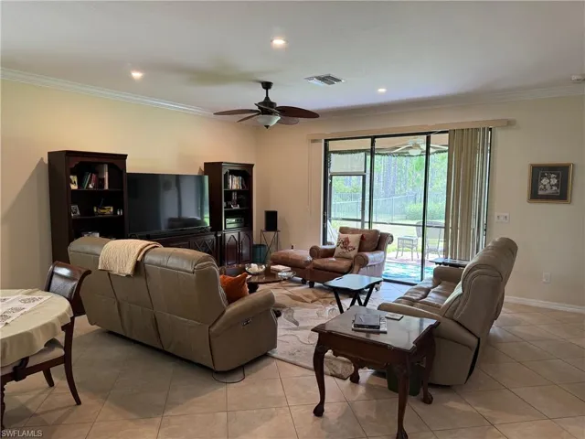Tiled living room with ornamental molding and ceiling fan