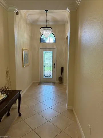 Tiled foyer featuring a notable chandelier and ornamental molding