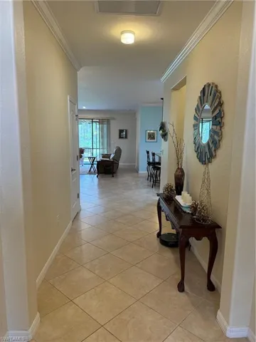 Corridor with crown molding and light tile floors