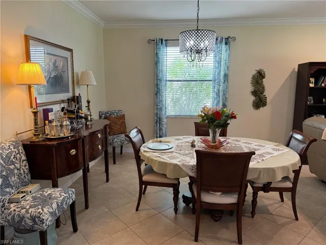 Tiled dining room with ornamental molding and an inviting chandelier