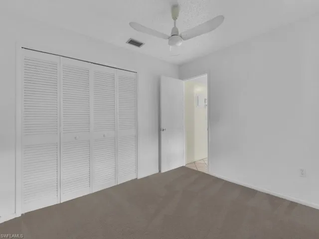 Unfurnished bedroom with a closet, carpet floors, a textured ceiling, and a ceiling fan