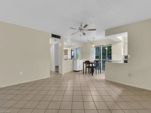 Living room with a textured ceiling, ceiling fan, and light tile patterned floors