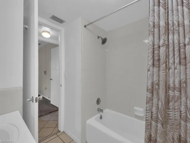 Bathroom with vanity, shower / bath combination with curtain, and light tile patterned floors