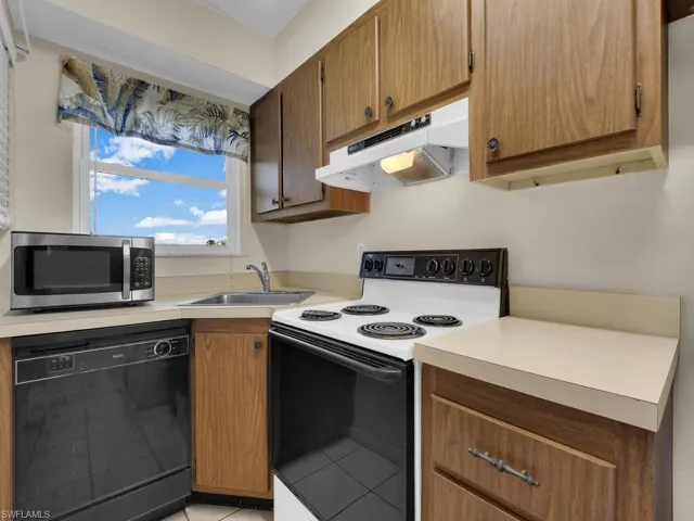 Kitchen with electric stove, dishwasher, stainless steel microwave, under cabinet range hood, and light countertops