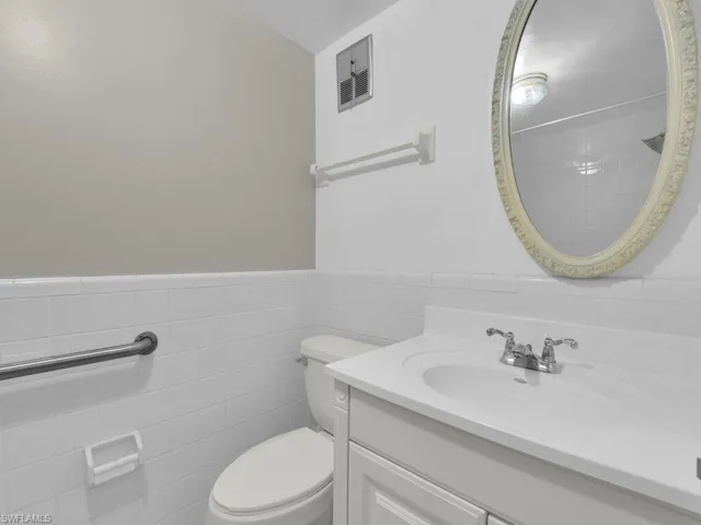 Bathroom with tile walls, vanity, and wainscoting