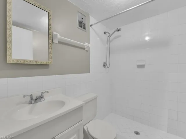 Bathroom with vanity, a stall shower, tile walls, and a textured ceiling