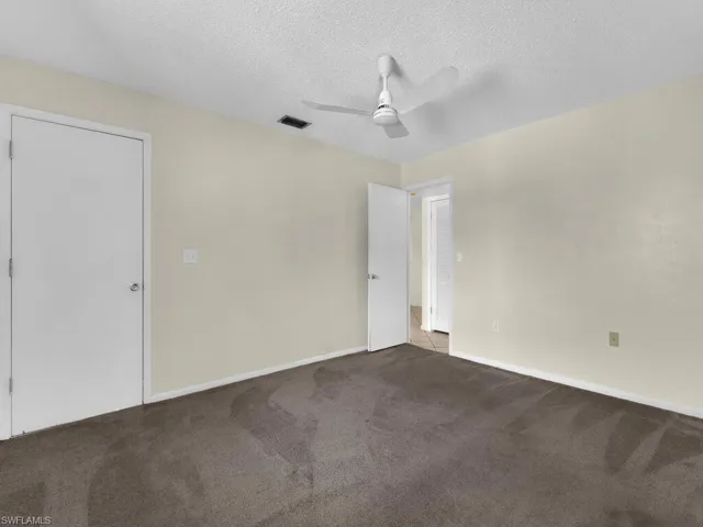 Unfurnished bedroom with a textured ceiling, carpet floors, and ceiling fan