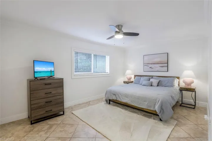 Tiled bedroom featuring ornamental molding and ceiling fan
