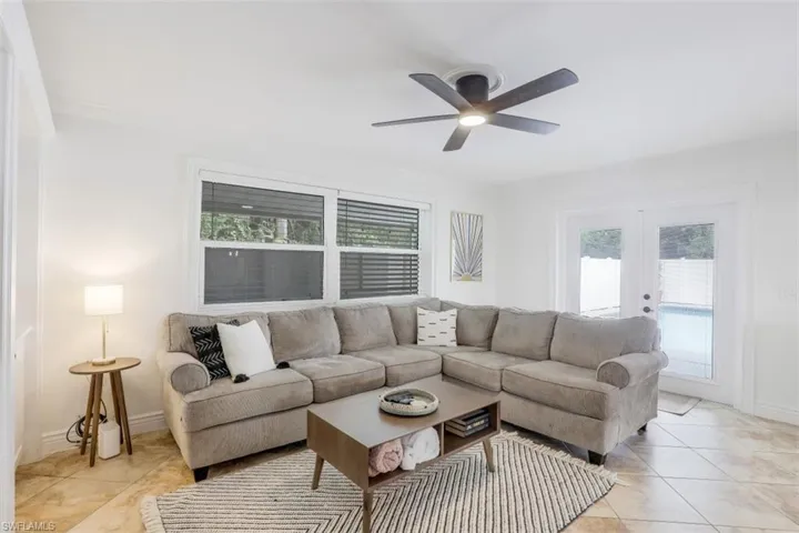Living room with crown molding, ceiling fan, french doors, and a wealth of natural light