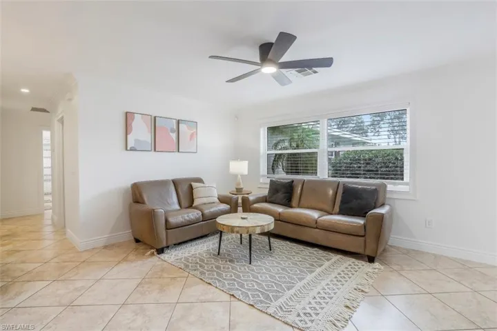 Tiled living room with ceiling fan and crown molding