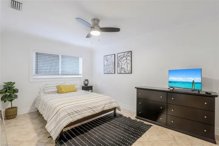 Bedroom featuring light tile patterned floors, crown molding, and ceiling fan
