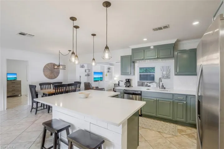 Kitchen with a breakfast bar, sink, green cabinetry, stainless steel appliances, and crown molding
