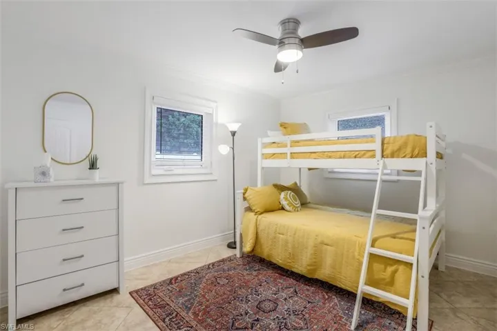 Tiled bedroom with ceiling fan and crown molding