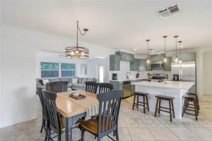 Dining space with ornamental molding, light tile patterned flooring, and sink