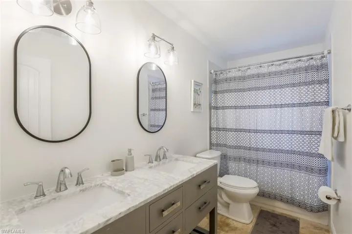 Bathroom with walk in shower, vanity, toilet, and tile patterned floors