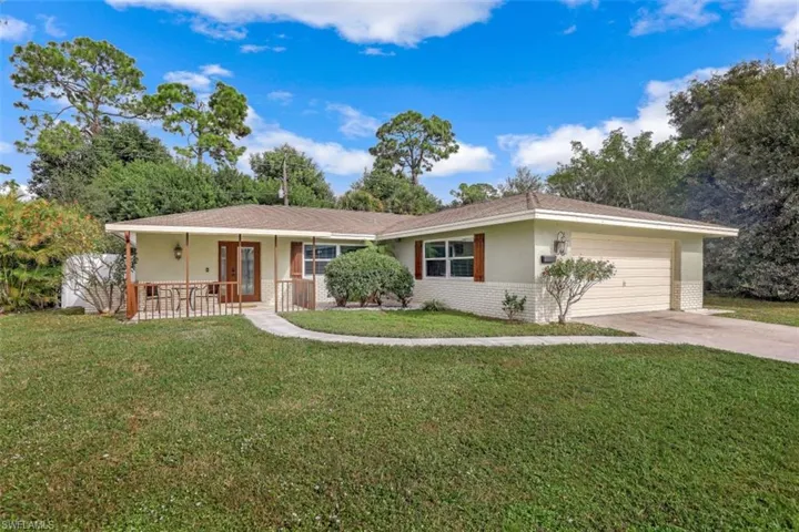 Ranch-style home featuring a garage, covered porch, and a front yard