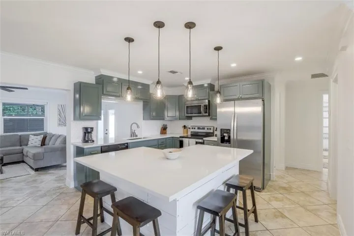 Kitchen featuring a kitchen bar, a center island, appliances with stainless steel finishes, and crown molding