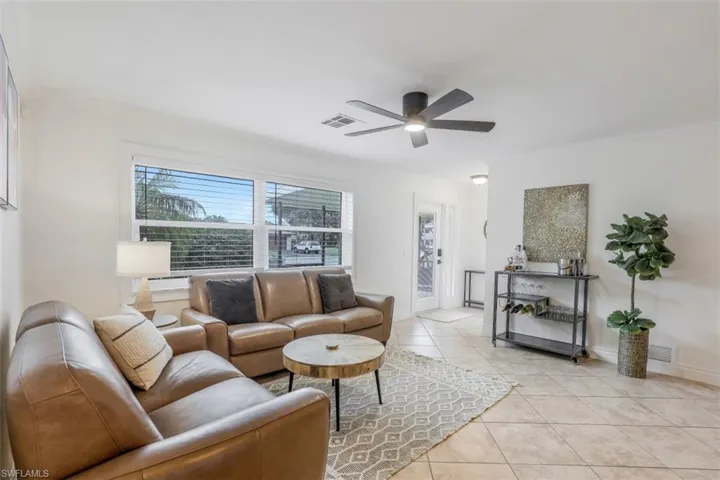 Tiled living room featuring ornamental molding and ceiling fan