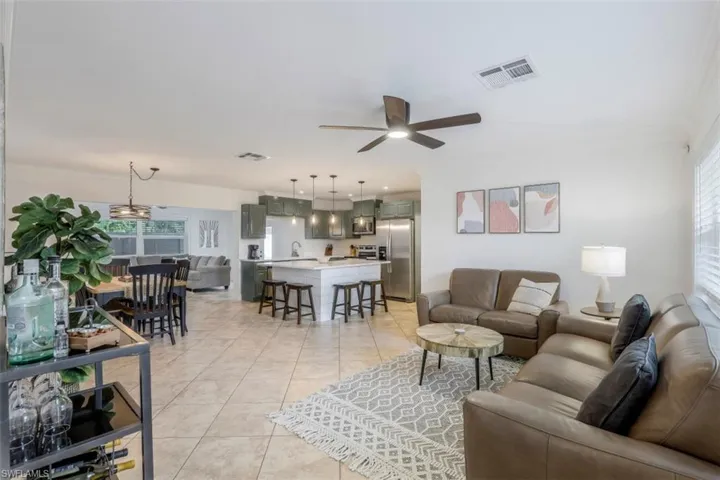 Living room featuring ceiling fan, light tile patterned flooring, and sink