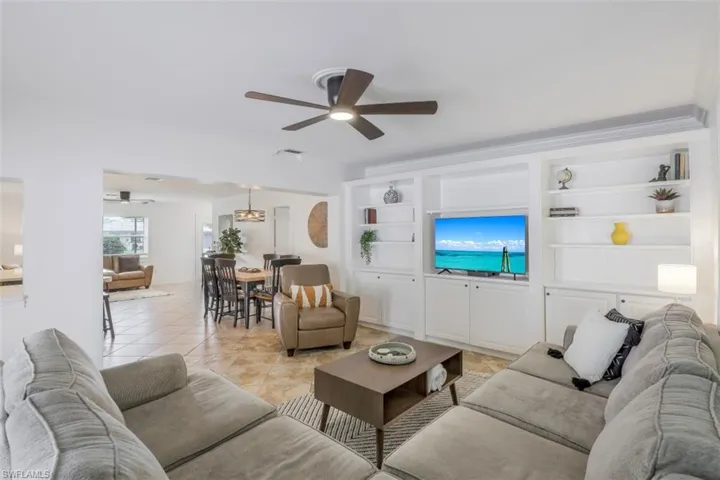 Tiled living room with ceiling fan and built in features