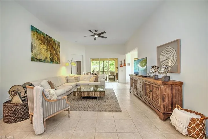 Spacious living area featuring neutral tile flooring, high ceilings, and a ceiling fan