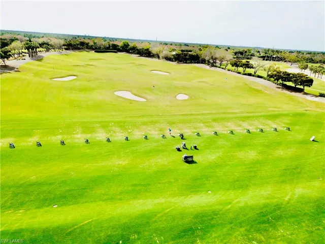 Expansive golf course featuring a driving range with individual hitting stations, multiple greens, and sand traps