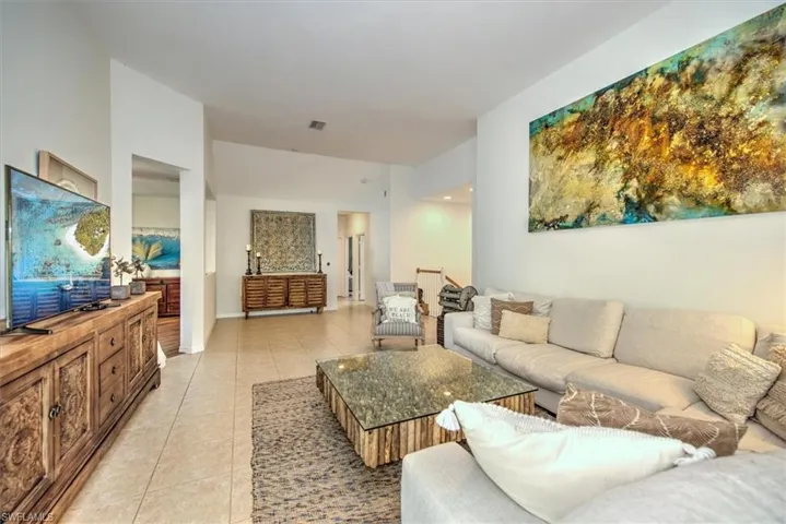 Spacious living area featuring neutral-toned tile flooring throughout and vaulted ceilings