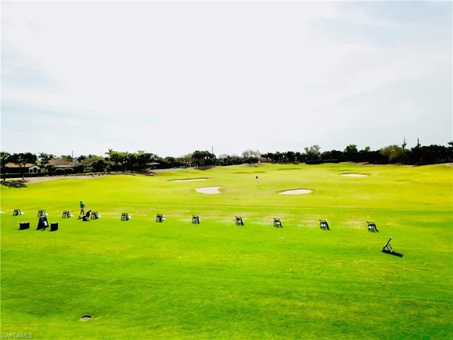 Expansive golf course featuring a driving range with multiple hitting stations, sand traps, and a putting green with a flag