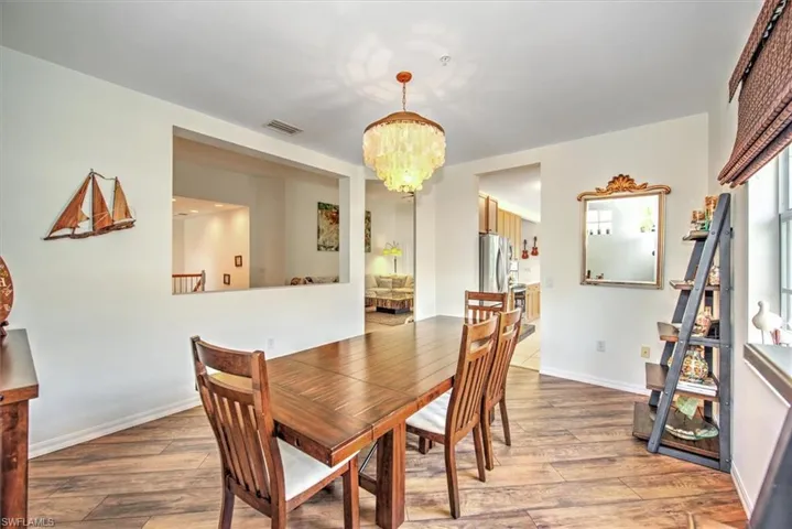 Dining area featuring wood-finish flooring, a decorative chandelier, and a pass-through window