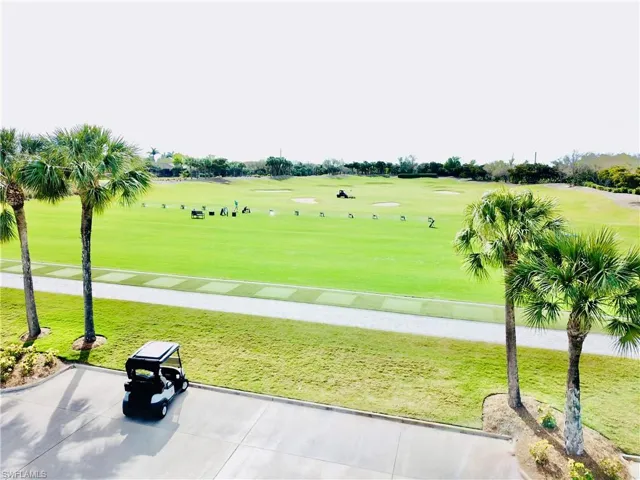 Expansive golf course with manicured greens and practice areas framed by mature palm trees