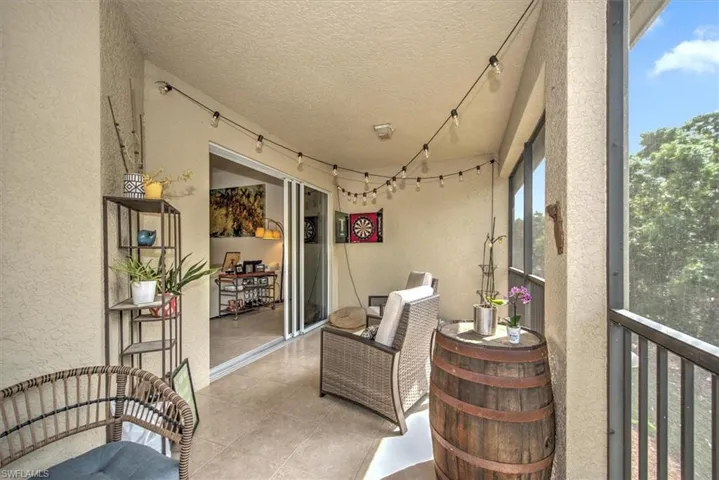 Screened balcony featuring textured stucco walls, tile flooring, and a sliding glass door entry