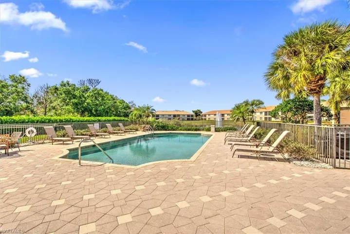 Resort-style pool with a paver deck, surrounded by palm trees and lush landscaping